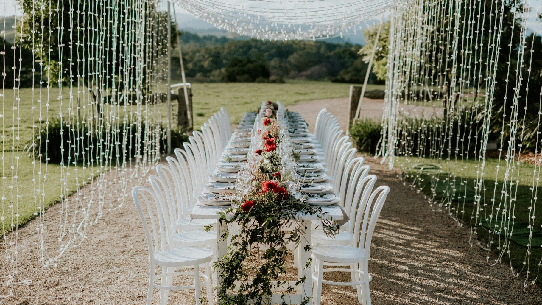 Table setting with fairy lights overlooking a garden path.